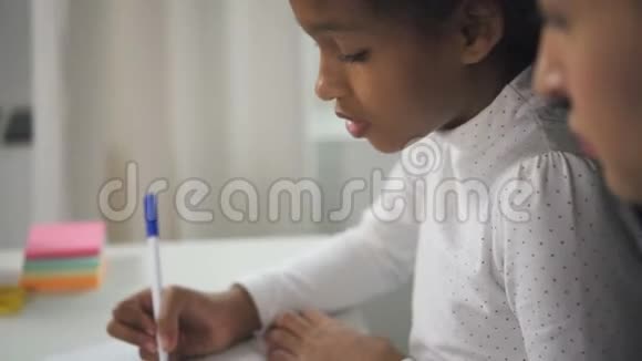 西班牙裔的孩子正在笔记本上做数学任务准备在家里上新课视频的预览图