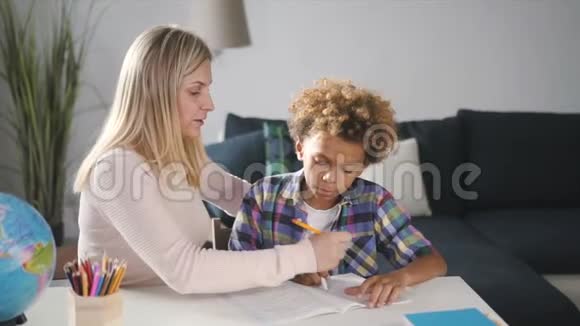 笑妈妈在学校作业中向儿子展示正确的决定和回答问题视频的预览图