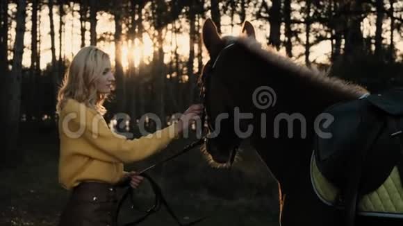 年轻女子牵着一匹漂亮的棕马在夕阳的余晖中缓缓地呼吸着视频的预览图