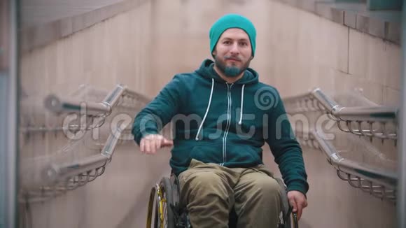 轮椅上的残疾人微笑着挥舞着他的手表现出令人鼓舞的手势视频的预览图