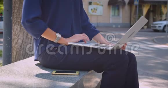 城市户外公园里年轻迷人的高加索女商人在笔记本电脑上打字的特写侧景视频的预览图