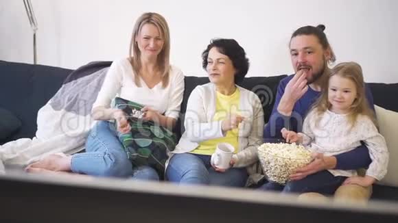 幸福的一家人坐在沙发上一起看电视一起吃爆米花视频的预览图