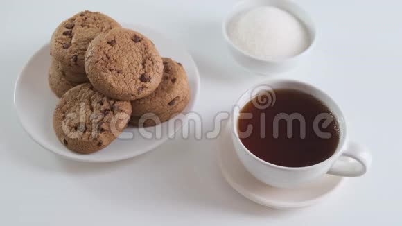 在一杯茶或咖啡中加入糖在白色的厨房桌子上放饼干快关门视频的预览图