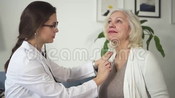 年轻护士拜访退休妇女并使用听诊器视频的预览图
