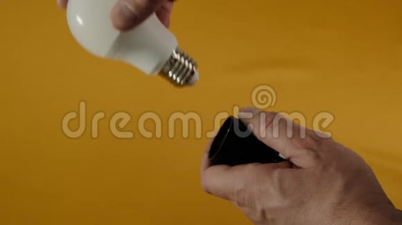 男性手扭转电器节省灯泡在白色桌子上快关门视频的预览图