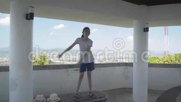 亚洲可爱的女孩穿着休闲装在蓝天的观景塔上快乐地跳舞视频的预览图