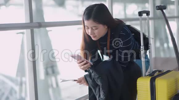 年轻旅客女性在机场等候时使用智能手机视频的预览图