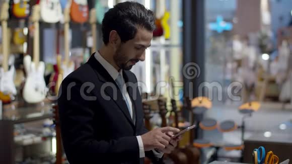 年轻英俊的企业站在一边使用智能手机视频的预览图