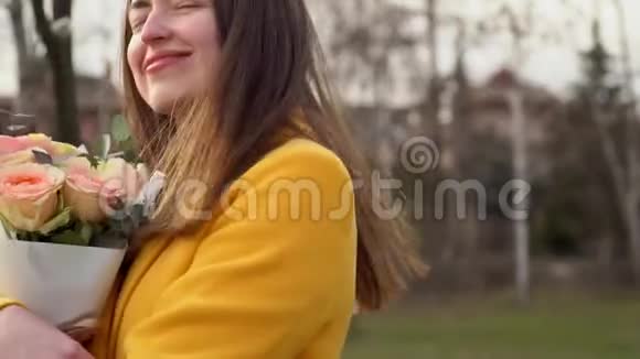 穿着黄色外套和玫瑰跳舞的快乐女人情人节概念恋爱中的女孩滑动运动视频的预览图