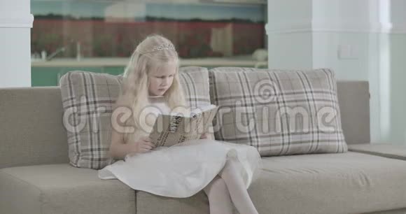漂亮的白人女孩穿着优雅的白色连衣裙坐在教练上当圣诞老人在后台散步时看书可爱视频的预览图