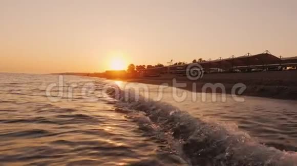 日落时一个年轻人在海浪中奔跑在度假村做运动视频的预览图