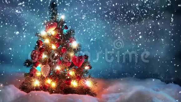 在白雪皑皑的夜晚用球和灯装饰着圣诞树当它轻轻地下雪时候视频的预览图