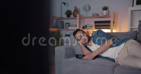疲惫的中东人独自躺在电视前的沙发上视频的预览图