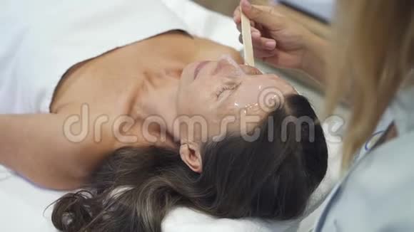 美丽的中年妇女在水疗中心买面膜视频的预览图