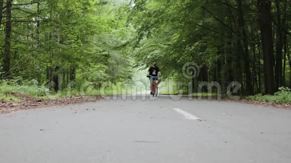 一个留胡子的人骑着自行车穿过森林公园视频的预览图