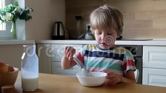 可爱的男孩4岁在家里的桌子上吃早餐玉米片和牛奶视频的预览图