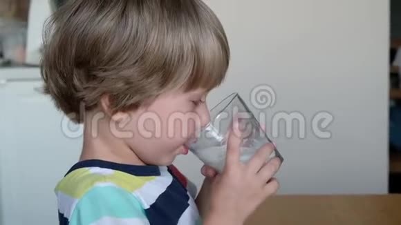 可爱的男孩4岁在家里的桌子上喝牛奶视频的预览图