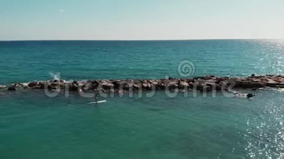 一个人在上吊小男孩冲浪鸟瞰美丽海景钻出的海石男人在游泳视频的预览图