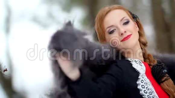 一个美丽的女孩在冬天的森林背景下肩上披着羽绒披肩视频的预览图