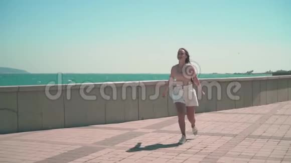 快乐的女孩沿着海边的长廊跑视频的预览图