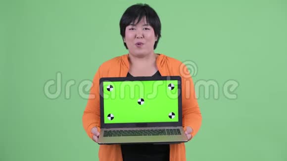 快乐年轻体重超重的亚洲女人一边说着一边展示准备好的笔记本电脑视频的预览图