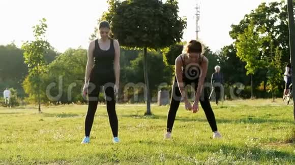 两个运动女孩在阳光公园一起训练健身健美操和伸展运动健康和运动视频的预览图