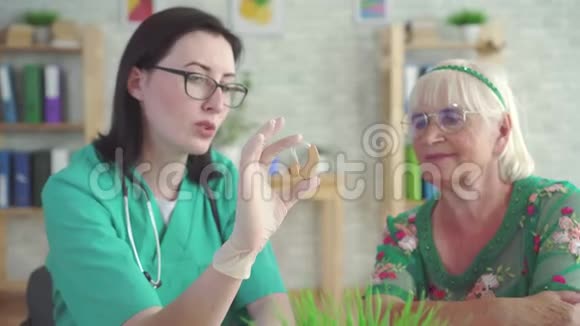 听力学家医生告诉一位老年妇女有关助听器视频的预览图