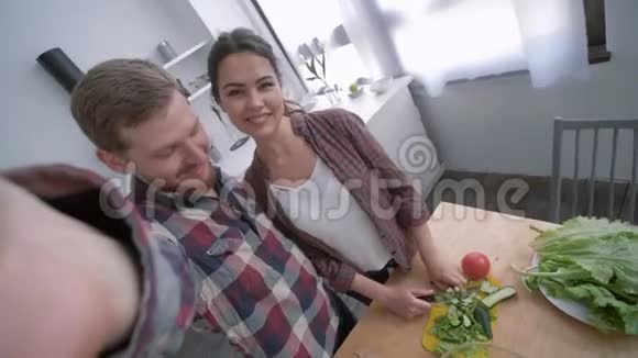烹饪家庭时间幸福夫妇在手机上自拍照片同时在早午餐上做蔬菜沙拉以获得健康视频的预览图