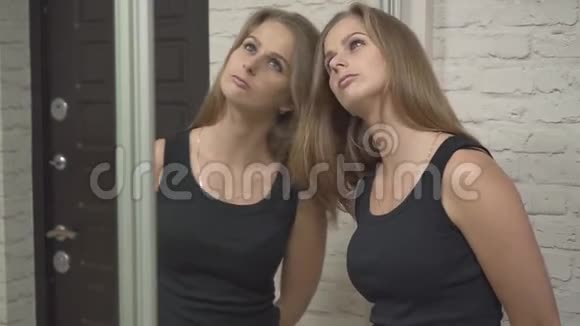 一个漂亮的女孩站在房子的前门一个金发女郎在一面大镜子里悲伤地看着自己视频的预览图