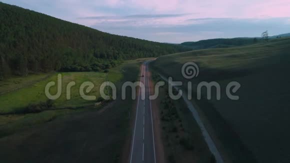 在阳光明媚的夏日黑色的汽车沿着沥青路穿过广阔的森林视频的预览图