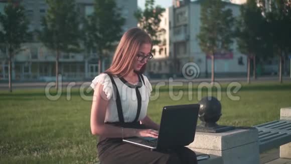 商务女性穿着白色衬衫和眼镜坐在长凳上在笔记本电脑上工作这个女孩对工作不满意生气视频的预览图