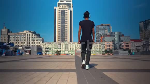 从后景看时髦的家伙听音乐走在城里视频的预览图