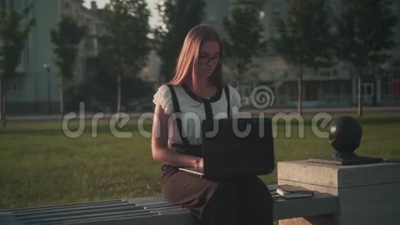 商务女性穿着白色衬衫和眼镜坐在长凳上为笔记本电脑工作女孩生气了关上笔记本电脑视频的预览图