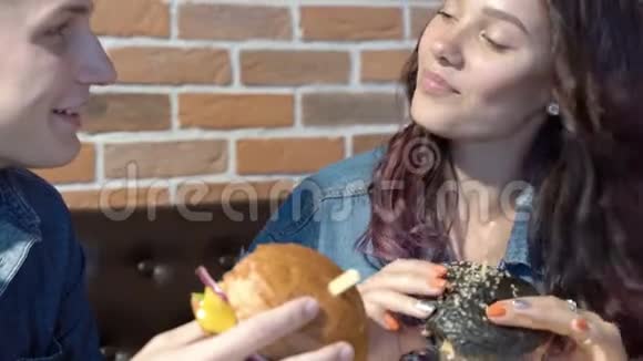 可爱的情侣在咖啡馆或家里聊天吃汉堡包视频的预览图