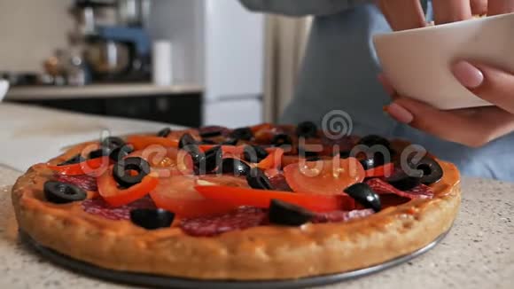 一个年轻女孩的手里撒着烤奶酪的披萨妻子为心爱的丈夫准备披萨视频的预览图