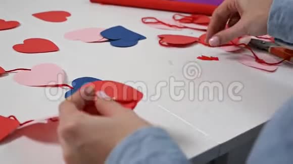 创意女孩用剪刀剪出红纸心花为情人制作明信片视频的预览图