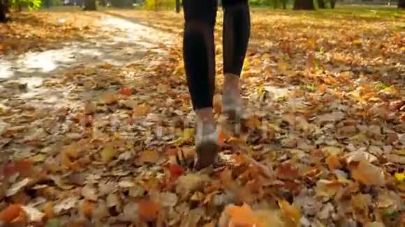 特写慢动作视频年轻女子穿着运动鞋在公园的小路上奔跑上面覆盖着黄色红色视频的预览图