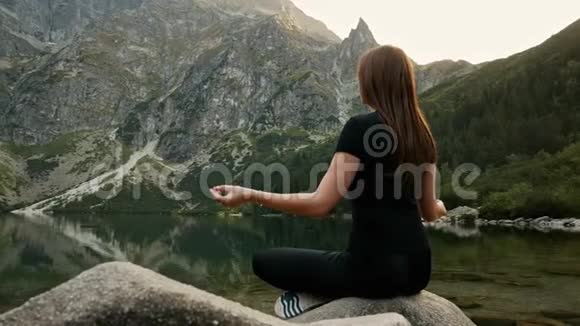 健康的年轻女子在山湖上冥想练习瑜伽享受高山上的宁静视频的预览图