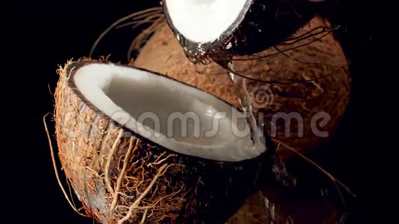 特写慢动作视频椰奶在黑色背景下慢慢流出破碎的椰子完美完美完美视频的预览图