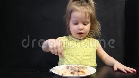 3岁的孩子在黑桌上用勺子吃熟饭和蘑菇视频的预览图