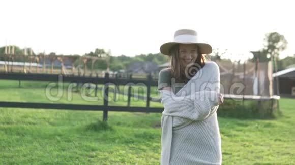 戴着帽子的漂亮女人在生态农场的夕阳下散步视频的预览图