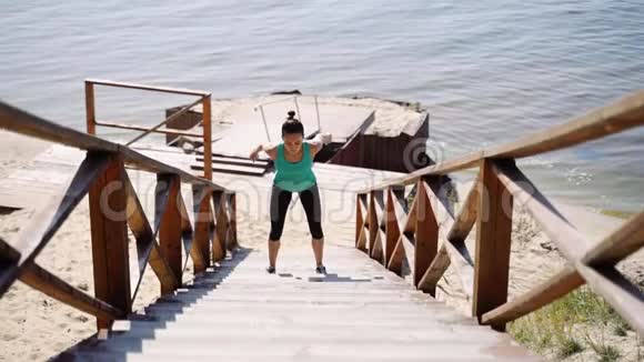 年轻女子在河边的木梯上跳蹲视频的预览图