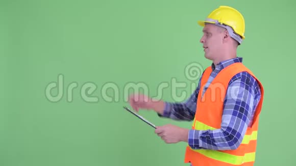 幸福青年建筑工人在剪贴板上阅读时指导的轮廓图视频的预览图