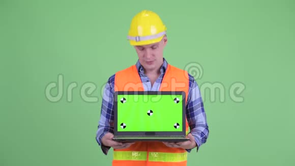 严肃的青年建筑工人手提电脑不点头视频的预览图