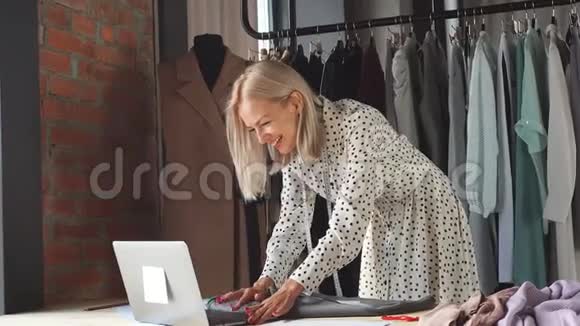漂亮的时装设计师看着笔记本电脑微笑着视频的预览图