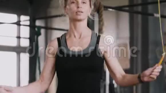 特写年轻漂亮的金发女人在大气健身房中用跳绳慢动作健康的生活方式视频的预览图