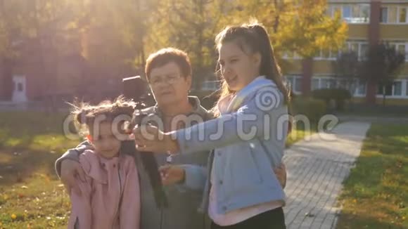 一个十几岁的女孩在公园里和他的妹妹和祖母拥抱在动作摄像机上放松自己视频的预览图