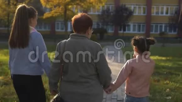 祖母带着两个孙女在日落时牵着手穿过小巷后景视频的预览图