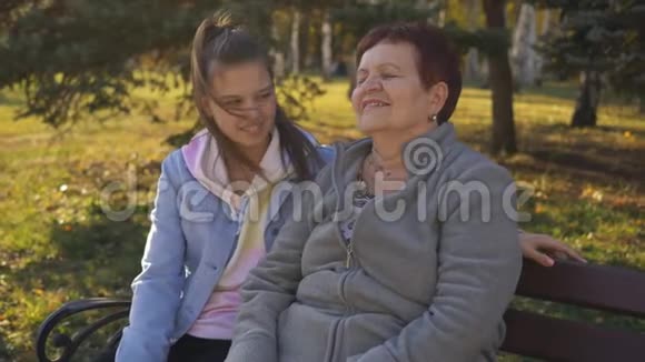 祖母和她的孙女一个十几岁的孩子坐在公园的长凳上说话视频的预览图