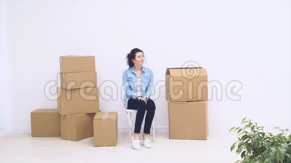 强壮的女人坐在大箱子附近装满了物品在白色的背景上被隔离4K视频的预览图